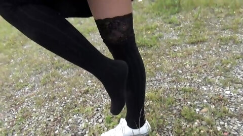 Schoolgirl in black knee socks and white shoes show under the skirt